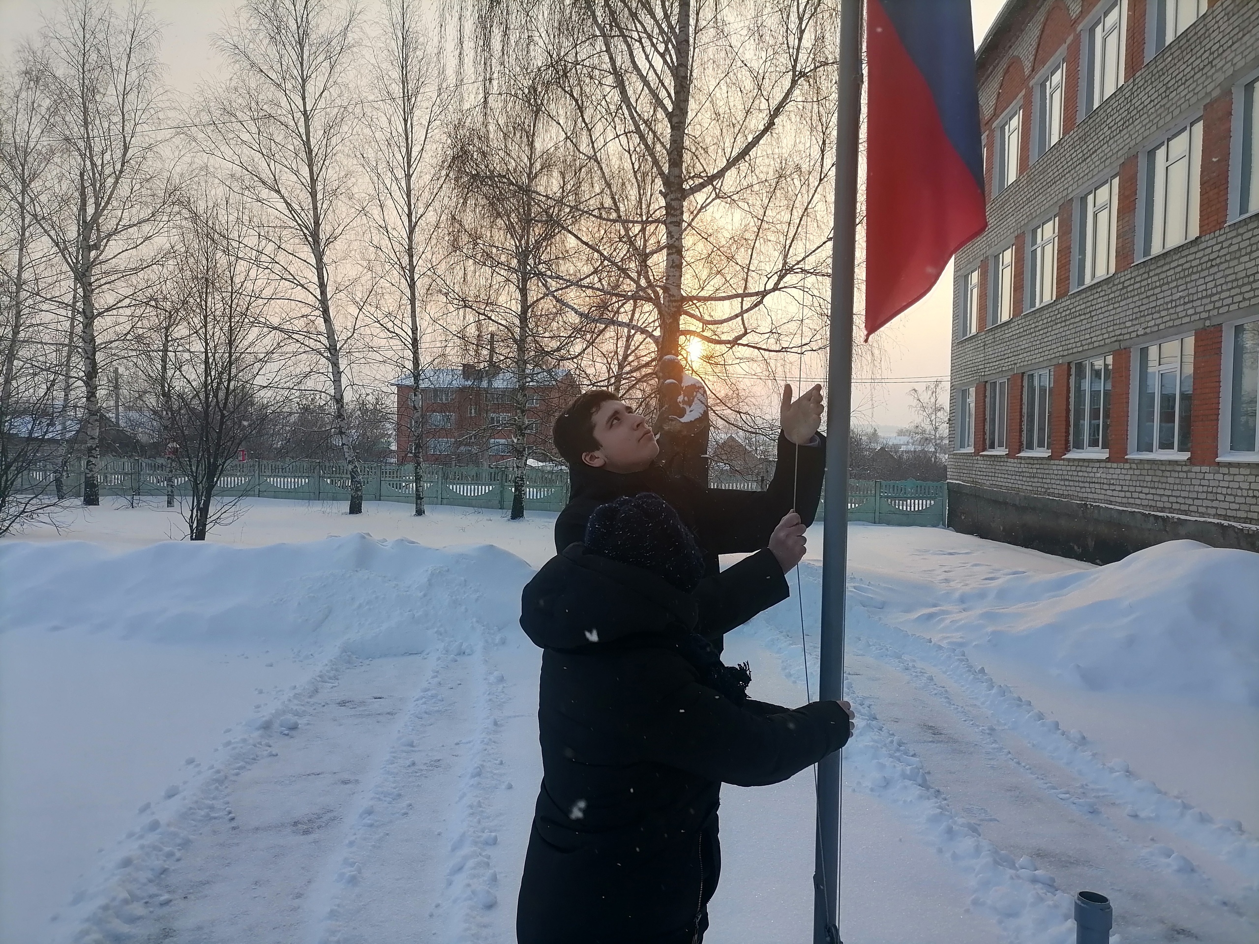 Поднятие флага на улице школьниками зимой. МБОУ Кочкуровская СОШ Дубенского района. Февраль снег в городе и флаг РФ.